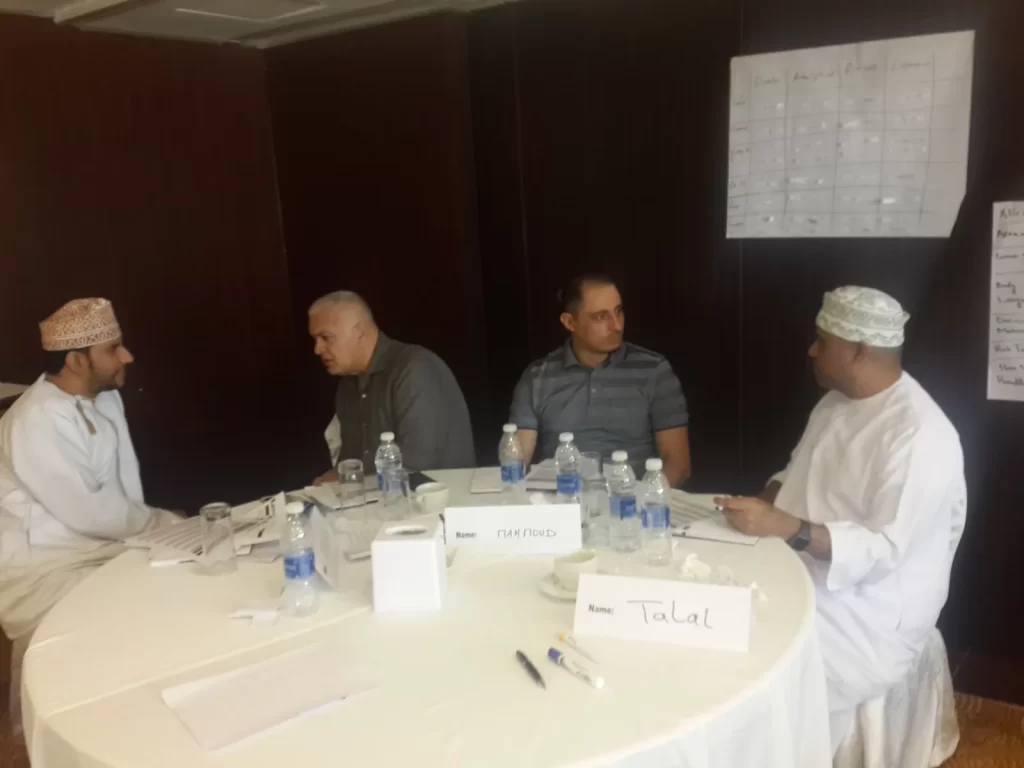 Participants in a group discussion around a table in Oman